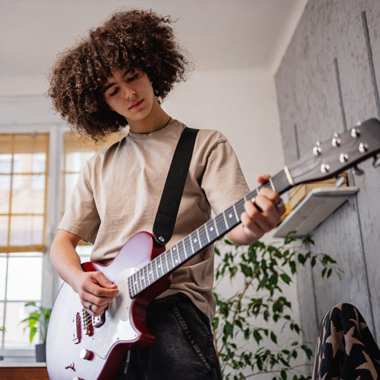 Happy teen boy playing guitar after getting started with pediatric treatment at Aris Clinic